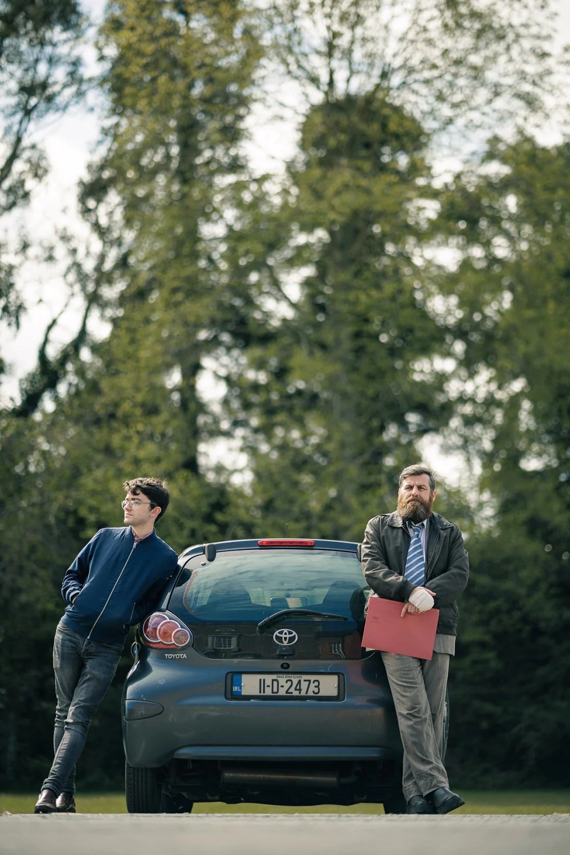 Two detectives wait at their car while holding a case file. A unit still from Irish crime noir Perdu.