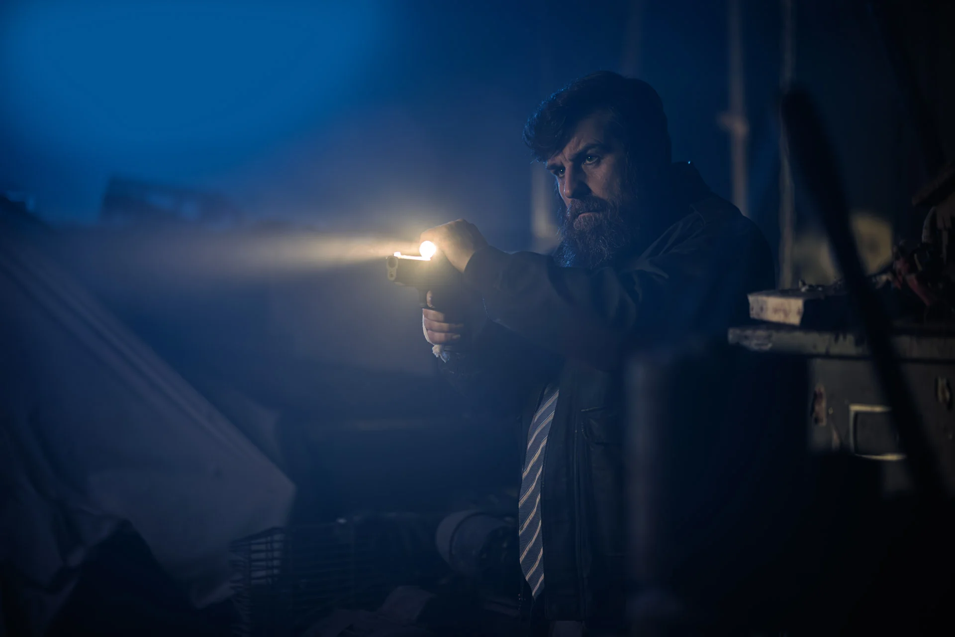 Detective Reilly scans a dark room aiming his torch and firearm.