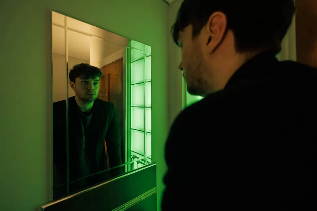 Film still from an Irish short film of a traumatised young man composing himself in a bathroom mirror.